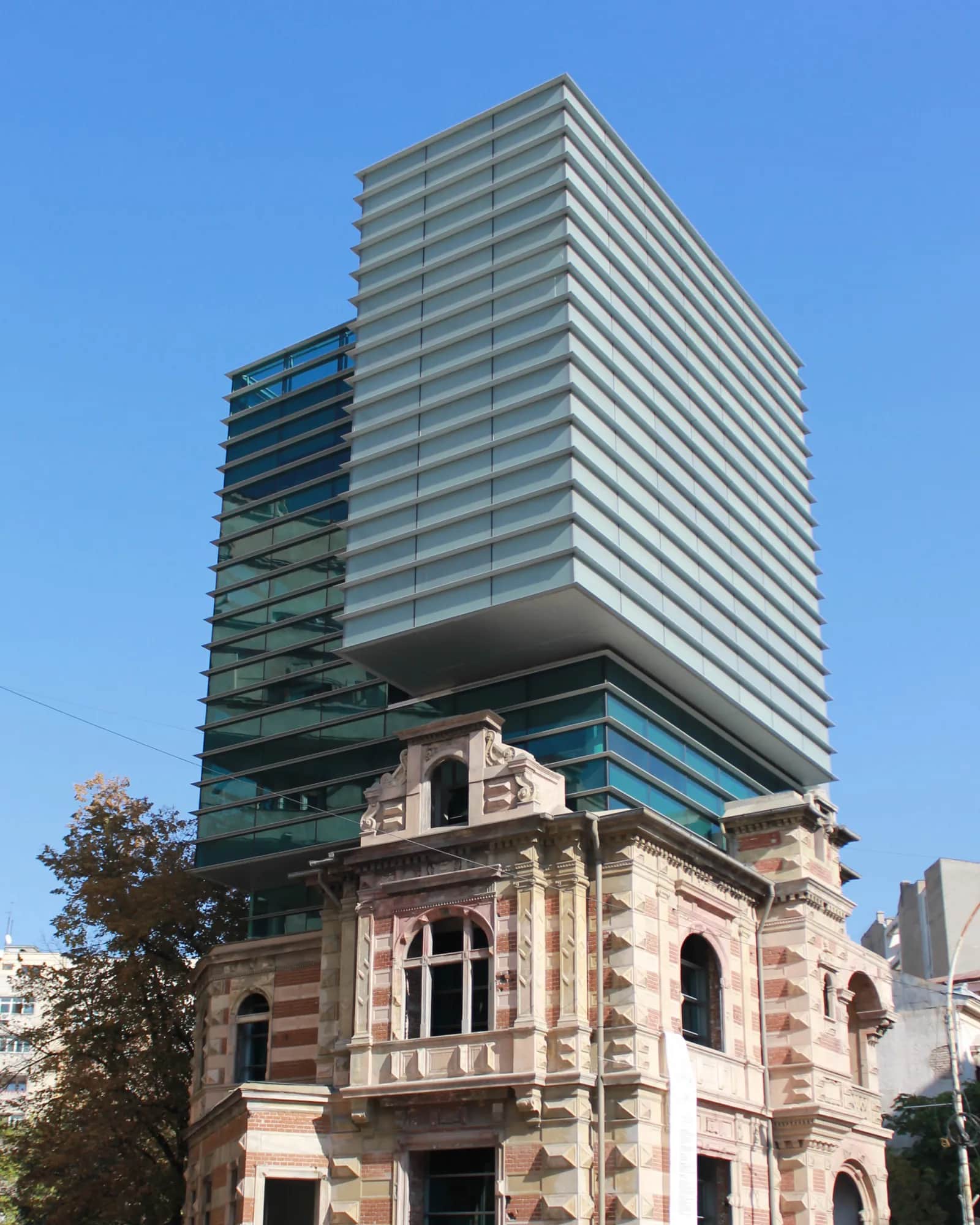 O clădire istorică din București, în fața unui turn contemporan din sticlă